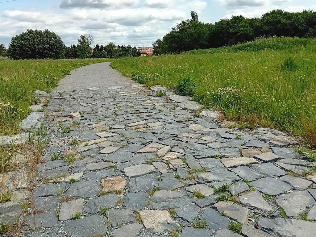 Kamenitý úsek v mlatové cestě pro odvod vody přes cestu